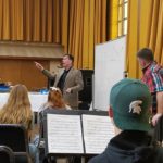 Band director pointing to a school band surrounding him.