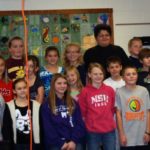 Group of children in a classroom setting smiling at the camera.