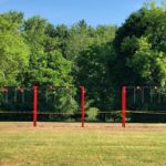 Set of red swing sets covered in caution tape.