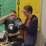 Two students interacting with a robotic toy made of legos.