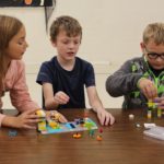 A group of young students playing with Legos.