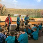 Students wearing blue school shirts standing in a history museum exhibit.