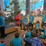 Students wearing blue school shirts standing in a history museum exhibit.