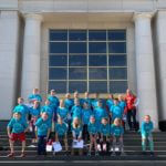 Group of students and a teacher standing on the steps of the Michigan Hall of Justice.