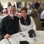 Older couple sitting at a dining table at an event.