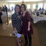 Two young women in dresses at an event posing for a photo.