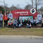 The Red Thunder Robotics team posing out front of the Laingsburg High School sign.