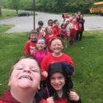 A line of young students wearing red shirts and smiling.